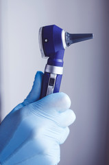 ENT medical doctor in gloves with the otoscope