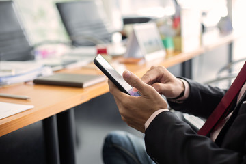 businessman hands searching for data on moblie phone with analyzing charts at his workplace.oncept