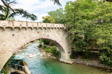 Fototapeta na wymiar View of the famous Steinerner Steg / Ponte Romano bridge, a two-arched, stone-built footbridge across the Passer in Merano, South Tyrol, northern Italy