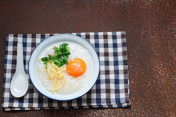 Delicious Rice soup with meat, egg and herbs on rusty metal wall with copy space.,hot food and healthy meal concept