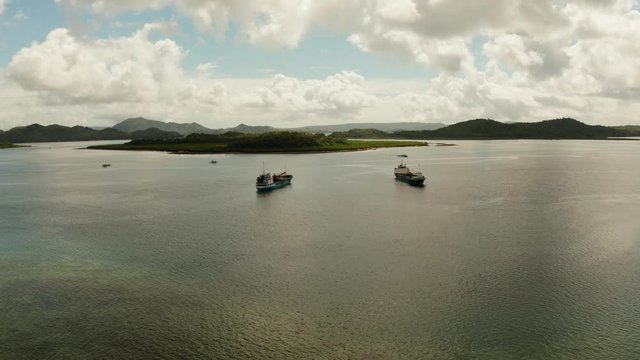 Cargo ships moored in a bay among tropical islands. Dapa Ferry Terminal. Siargao, Philippines.