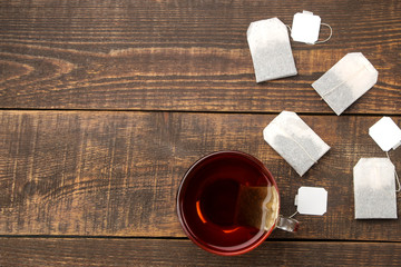 Cup with tea and tea bags on a brown wooden table. top view with space for text