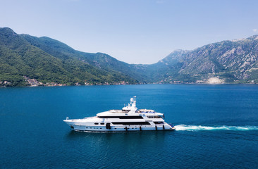 View on the luxury yacht in Montenegro. Blue sea water background from air. Mountains and sea...