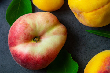 Nice yummy fresh apricots and peaches with green tree leaves on dark texture surface. Summer fruits.