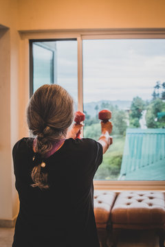 Senior Indian Woman Exercising At Home Using Body Weights And Dumbbells. Ethnic Indian Background With Outdoor Background Scenes. Help In Reducing Diabetes And High Blood Pressure, Endemic  In India. 