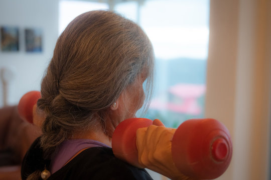 Senior Indian Woman Exercising At Home Using Body Weights And Dumbbells. Ethnic Indian Background With Outdoor Background Scenes. Help In Reducing Diabetes And High Blood Pressure, Endemic  In India. 