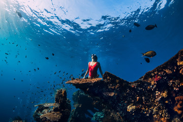 Woman freediver glides with fins at wreck ship. Freediving in blue ocean near wreck