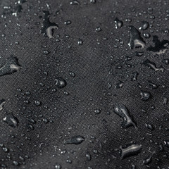 dark gray waterproof hydrophobic cloth closeup with water drops selective focus background