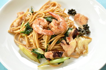 spicy stir fried spaghetti seafood with pepper and basil leaf on plate