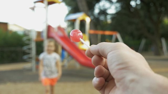 Stranger on playground offers candy to child. Kids in danger. Children safety protection. Suspicious adult man spying on kids and calls a child to himself. kidnapping concept, first-person view