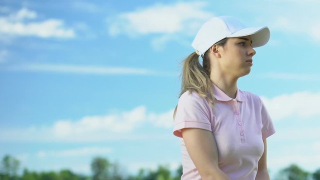 Nervous woman training to swing and hitting balls playing golf on country course