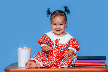 Cute one year old mixed race Asian Caucasian german girl wearing red dress smiles sweetly looking...