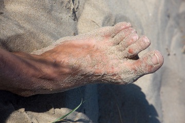 nackter Fuss mit Sandkörnern am Sandstrand
