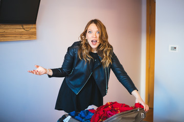 Shocked woman opening suitcase (the baggage of another person) in hotel room -  lost and found...