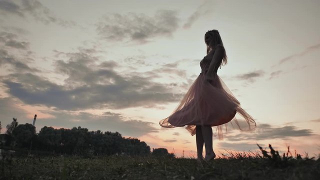 The girl in the dress swirls magically at sunset.