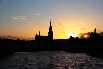 Sunset in an old European city (town) on a river. Dark silhouette of towers and buildings. Denmark