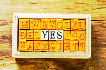 木目の上に置いたハンコ　YES の文字と木目の背景　メタリックにしました