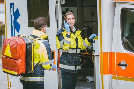 Medics in front of ambulance talking to headquarters using radio