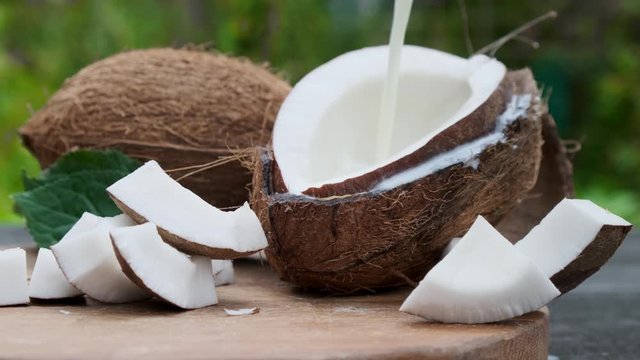 Pouring fresh coconut milk on wooden table.