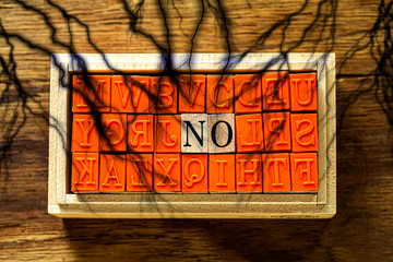 木目の上に置いたハンコ　NO の文字と木目の背景と黒の稲妻（雷）