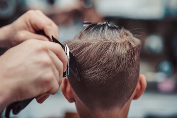 Naklejka premium Boy getting haircut by barber in barbershop.