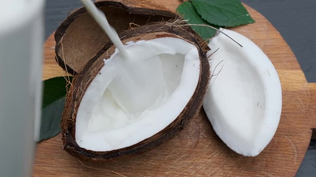 Pouring fresh coconut milk on wooden table.