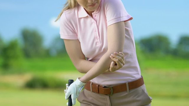 Woman trying to hit golf ball but feeling elbow pain rising club, joint problems