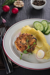 Minced meat cutlets with mashed potatoes on white plate over black wooden background. Top view, flat lay
