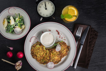 Potato pancakes on a white plate. Fresh vegetable salade and lemonade drink. Lunch time 12pm