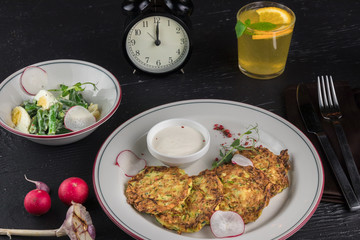 Potato pancakes on a white plate. Fresh vegetable salade and lemonade drink. Lunch time 12pm