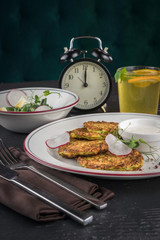 Potato pancakes on a white plate. Fresh vegetable salade and lemonade drink. Lunch time 12pm