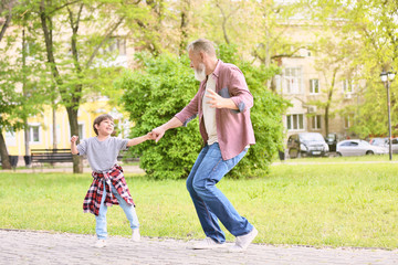 Fototapeta premium Cute little boy and his grandfather walking in park