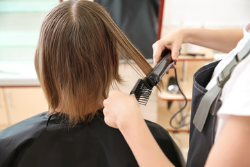 Fototapeta na wymiar Female hairdresser working with client in salon, closeup