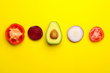 Fresh avocado and vegetables on color background