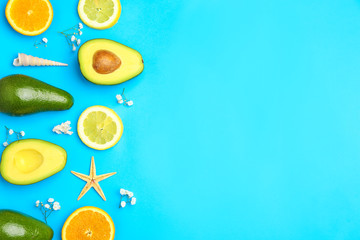 Fresh avocado, citrus fruits and sea shells on color background