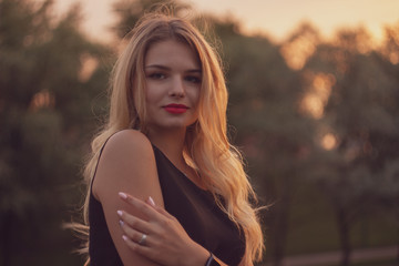 Young smiling blonde hair woman portrait on sunset in nature