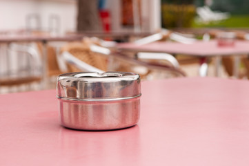 Steel ashtray on a table outside a hotel bar.