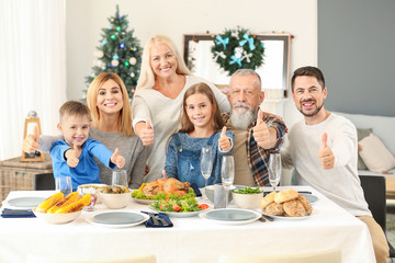 Happy family showing thumb-up gesture during Christmas dinner at home
