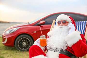 Cool Santa Claus with cocktail talking by mobile phone on riverside