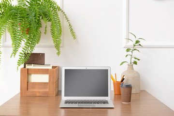 Fototapeta premium Stylish workplace with modern laptop near white wall