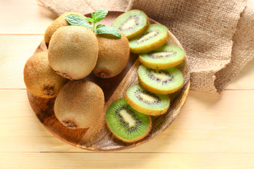 Plate with tasty ripe kiwi on wooden background