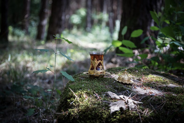 Eastern black tea in glass at the forest. Eastern tea concept. Armudu traditional cup. Green nature background.