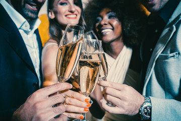 Men and women celebrating party while clinking glasses with sparkling wine