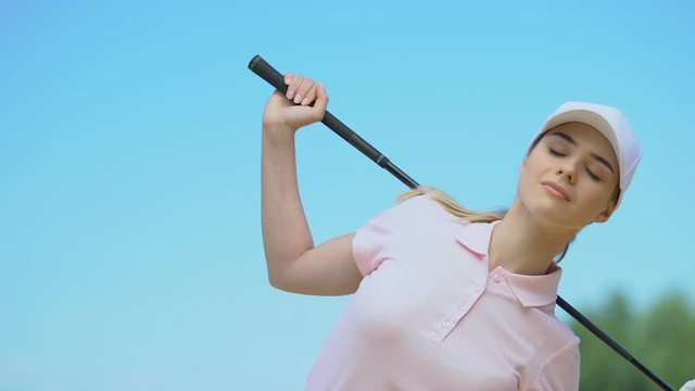 Woman golfer bending sides with club on shoulders warming up back muscles