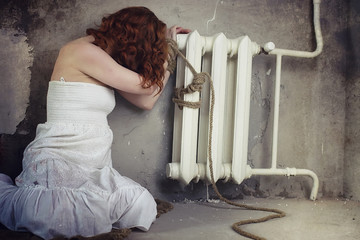 Young girl tied up on the floor. The abducted girl. The victim of violence sits on the floor with tied hands. Domestic violence.