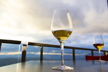 two glasses of white wine on reastaurant table on outdoor terrace with beutiful view