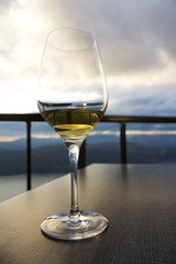 glass of white wine on restaurant outdoor table on background of blue sky