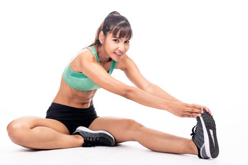 Fitness woman stretching isolated in white background. Asian girl in full body shot. Leg stretch sitting on floor big happy smile.