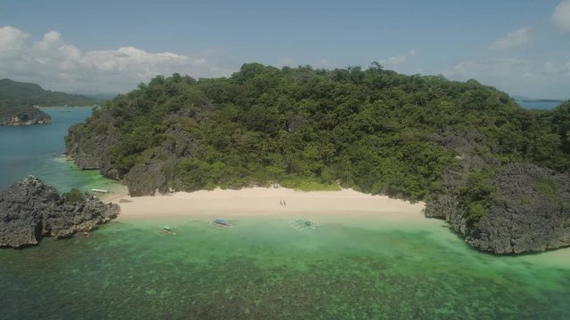 Aerial view Matukad island with sand beach and turquoise water in blue lagoon among coral reefs, Caramoan Islands, Philippines. Landscape with sea, tropical beach.