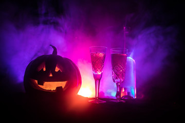 Two glasses of wine and bottle with Halloween - old jack-o-lantern on dark toned foggy background....